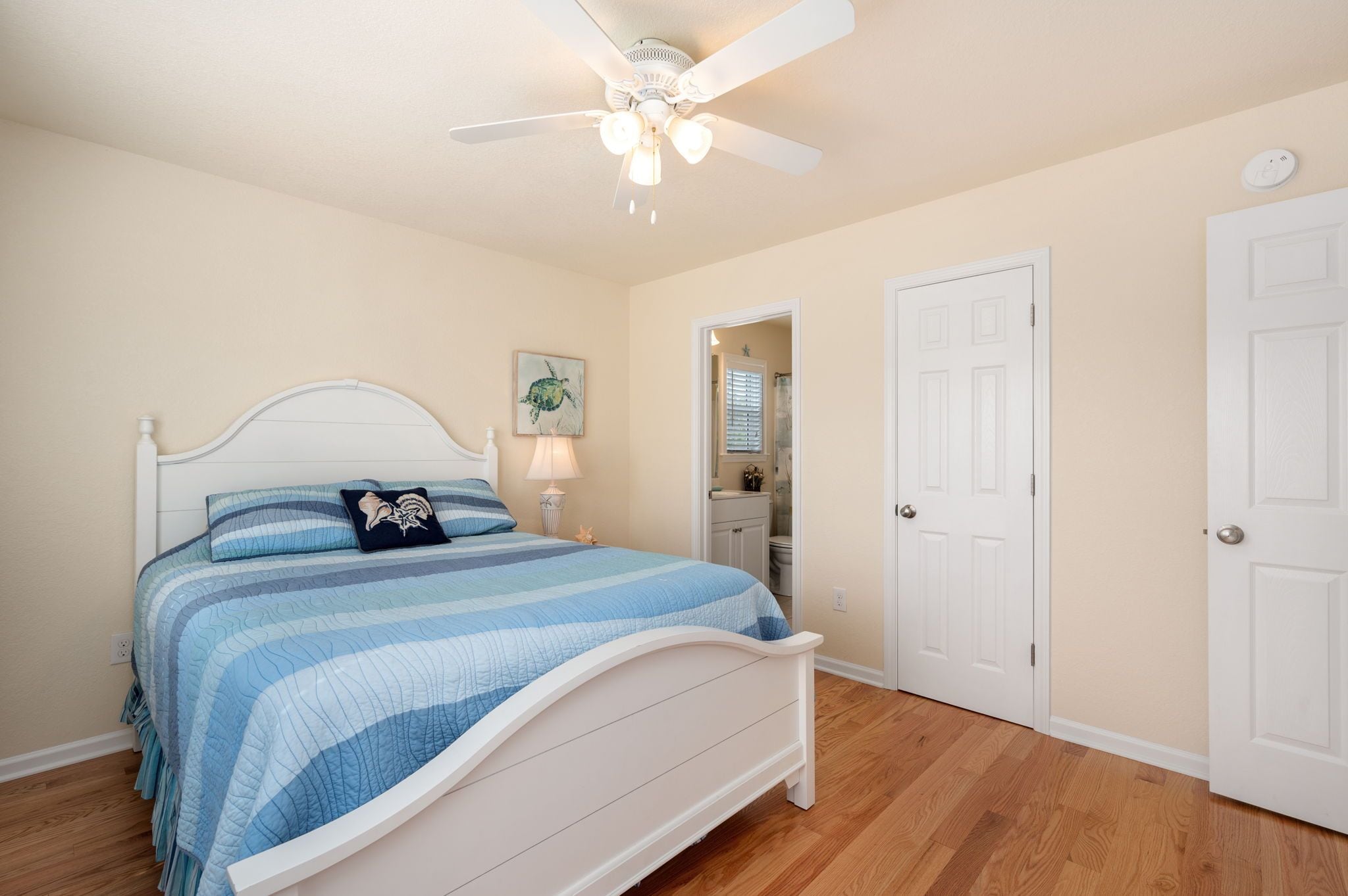 A bedroom with a bed, a ceiling fan, and a door.