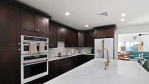 A modern kitchen with dark wood cabinets, stainless steel appliances, and a marble countertop. - Palm Tree Paradise Tampa (Tampa)