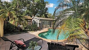 A backyard with a swimming pool, surrounded by palm trees and a house. - Palm Tree Paradise Tampa (Tampa)