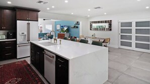 A modern kitchen with dark cabinets, a white island, and a red rug. - Palm Tree Paradise Tampa (Tampa)