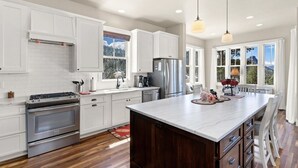 A modern kitchen with white cabinetry, stainless steel appliances, and a large island. - Spectacular Views of Long's Peak- 10 min to town-3 full bath plus 2 half bath (Estes Park)