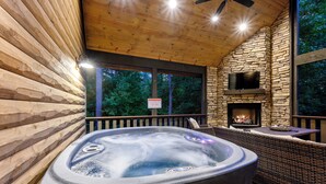 A hot tub with a stone fireplace and a wicker seating area. - It's the Little Things, Creekside, Hot Tub, Firepit, Great Location (Broken Bow)