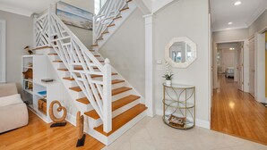 A staircase with white railings and wooden steps, leading to a hallway with a glass console table and a mirror. - Fantastic Marsh View E. Beach-Between Gould's Inlet & Coast Guard. Walk to beach (St. Simons Island)