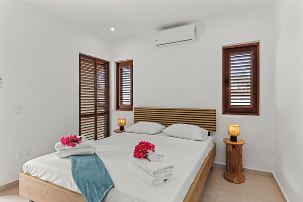 A neatly made bed with white linens, a wooden headboard, and two bedside lamps.