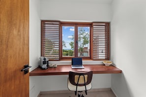 Une pièce d’angle avec un bureau en bois, un ordinateur portable, une machine à café et une chaise.