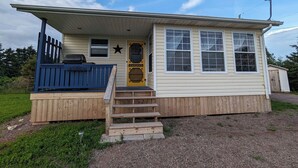 A small wooden house with a porch, a star decoration, and a wooden fence.