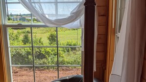 A room with a large window, a black leather chair, and a wooden coat rack.