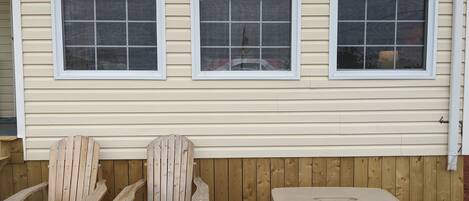 A wooden deck with two Adirondack chairs and a small table.
