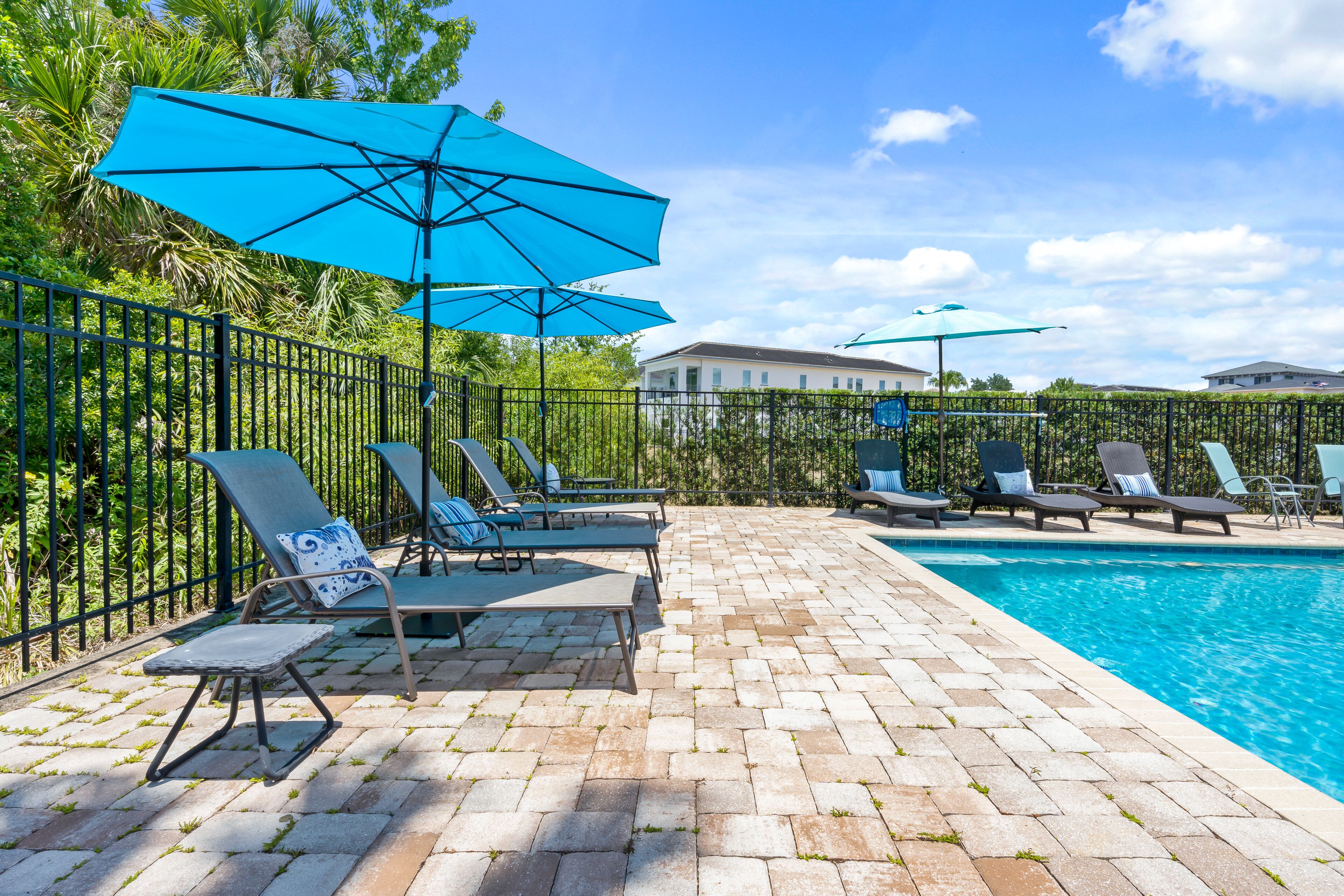 Ein Poolbereich mit Liegestühlen und Sonnenschirmen, einer Ziegelterrasse und einem Pool.