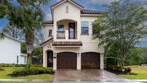 A two-story house with a front porch, a garage, and a well-maintained lawn. - Games Room | Private Pool with Built in BBQ | 8 Miles to Disney (Kissimmee)