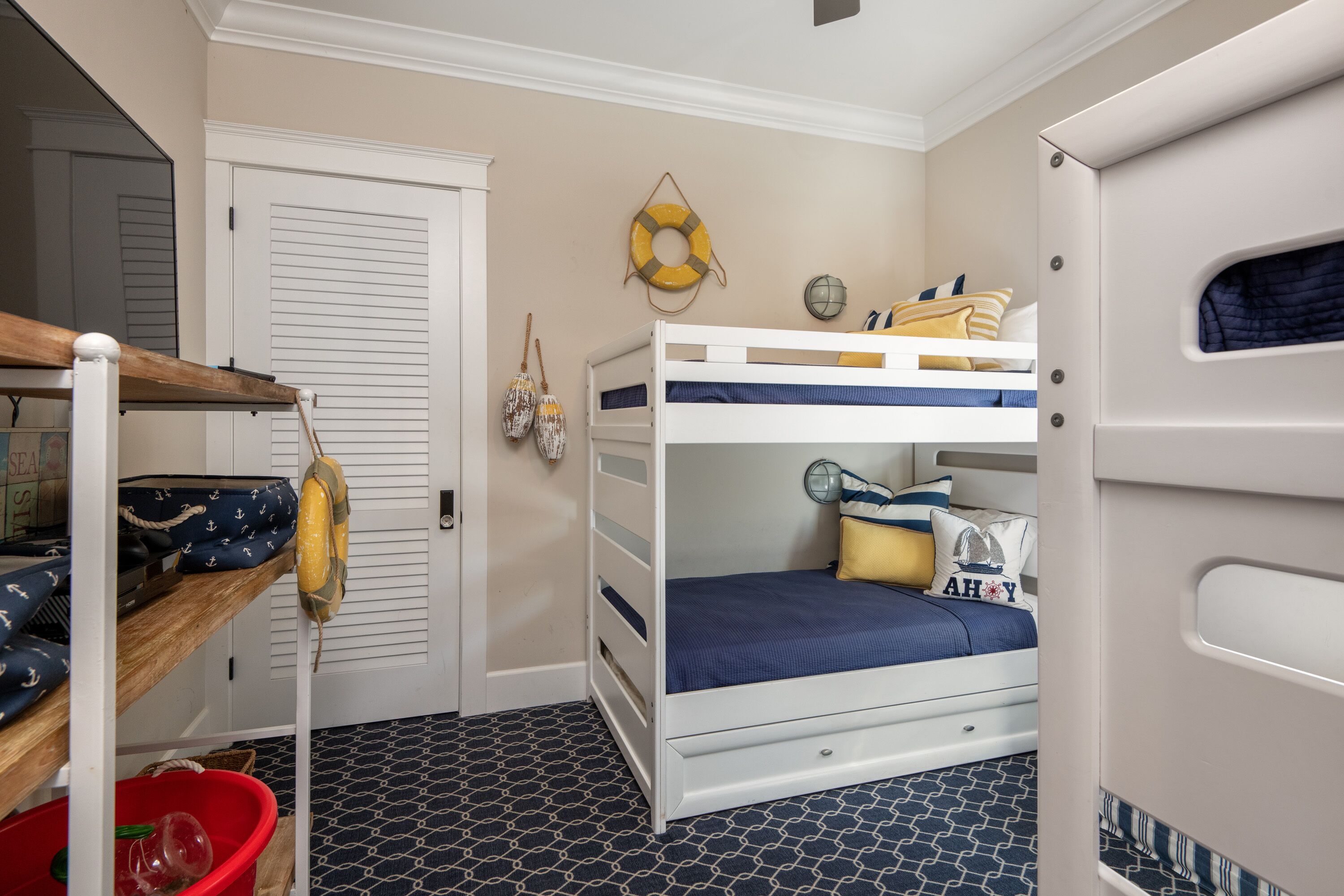 A bunk bed room with a nautical theme, including a life preserver on the wall and a ship's wheel.
