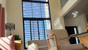 Ein geräumiges Wohnzimmer mit großem Fenster, einer Couch, einem Sessel und einem Couchtisch.