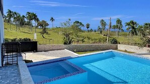Ein rechteckiger Swimmingpool mit Fliesenrand, umgeben von einer Steinmauer und einer gepflasterten Terrasse.