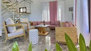 Ein geräumiges Wohnzimmer mit hoher Decke, einer Treppe und einer modernen Kronleuchter.