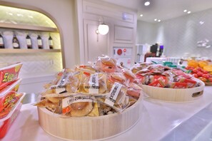 A buffet with various food items, including packaged snacks and fresh fruits.