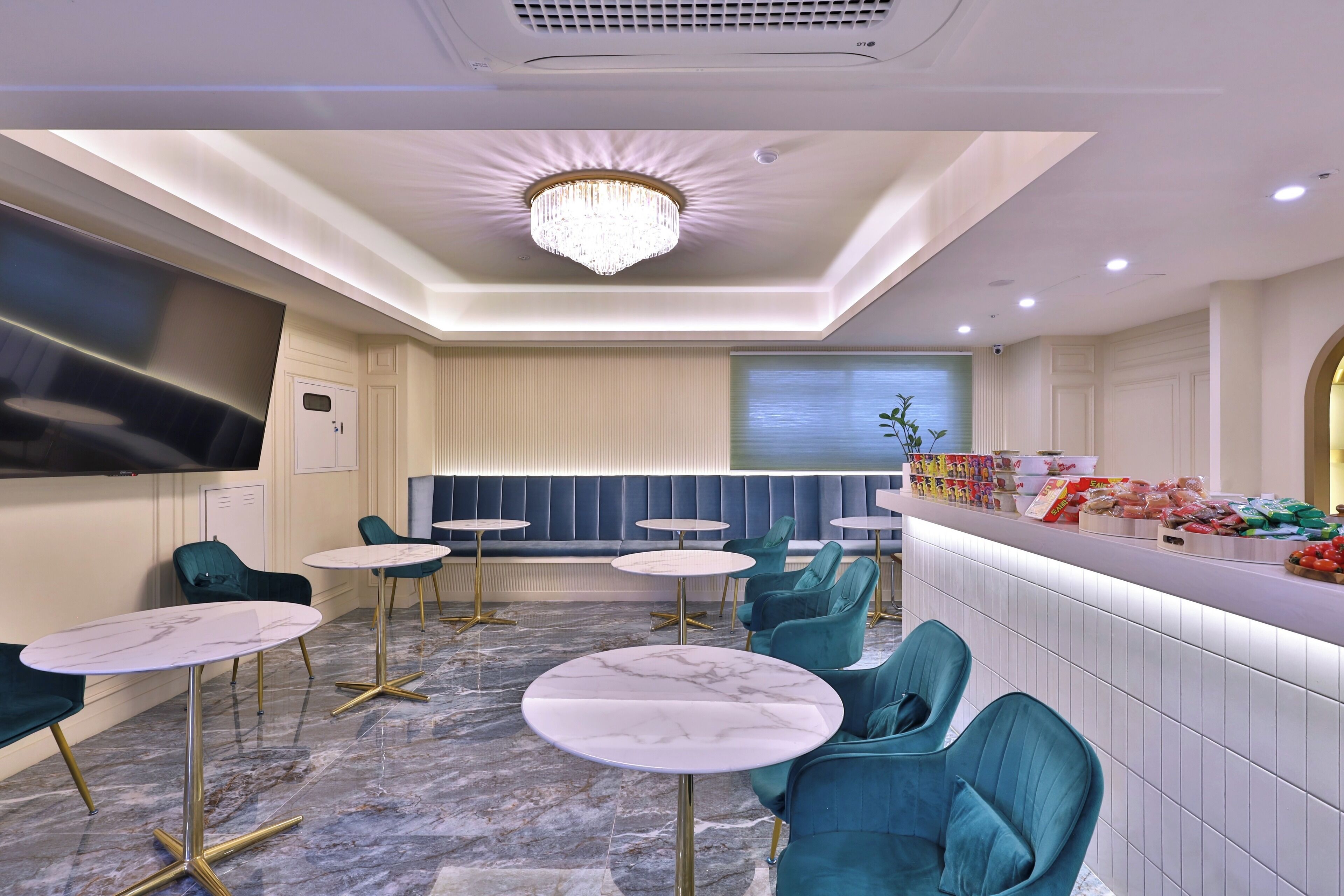 A modern hotel lobby with marble flooring, teal chairs, and a central seating area.