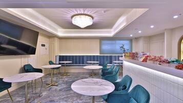 A modern hotel lobby with marble flooring, teal chairs, and a central seating area.