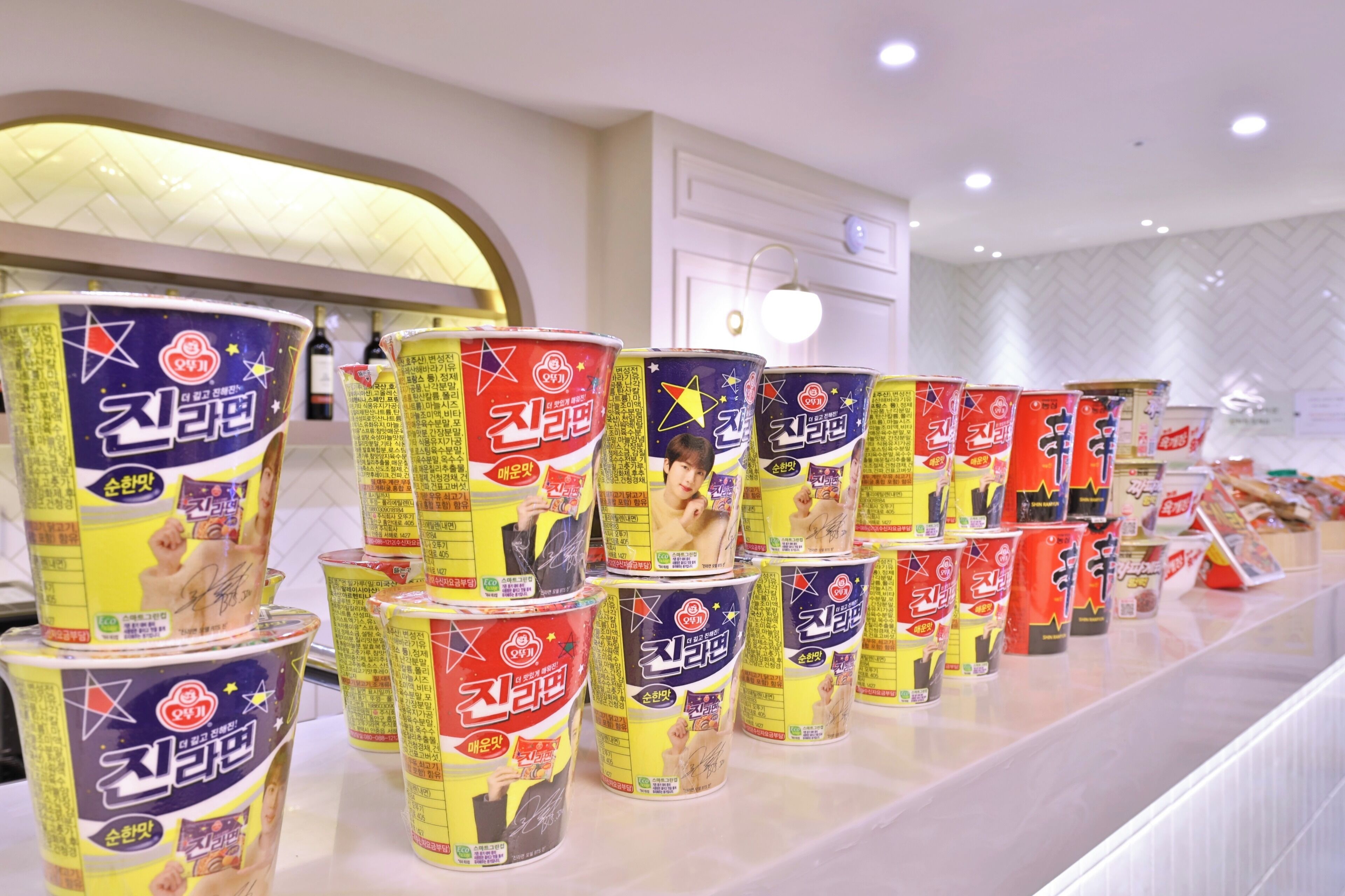 A row of stacked cans of a beverage on a counter in a brightly lit room with a modern design.