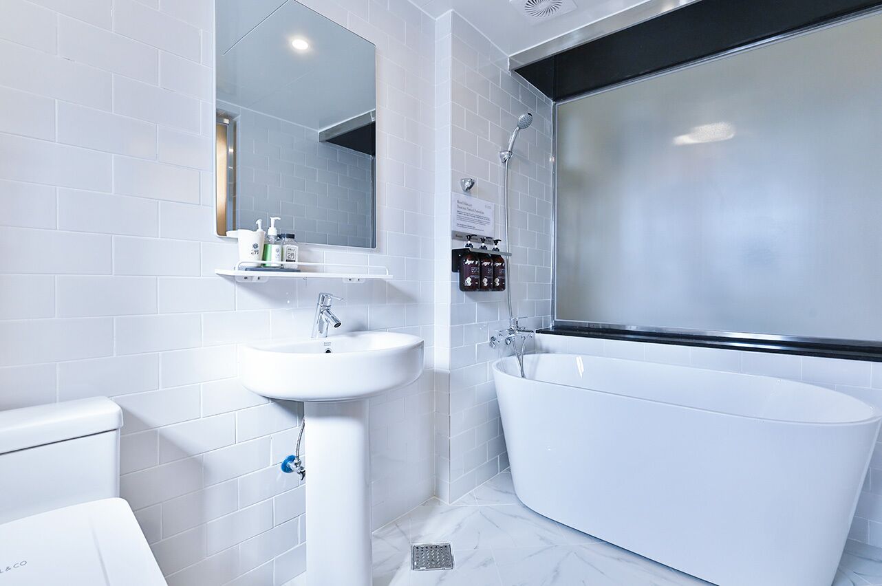 Un bagno moderno con lavandino, specchio e vasca da bagno bianchi.