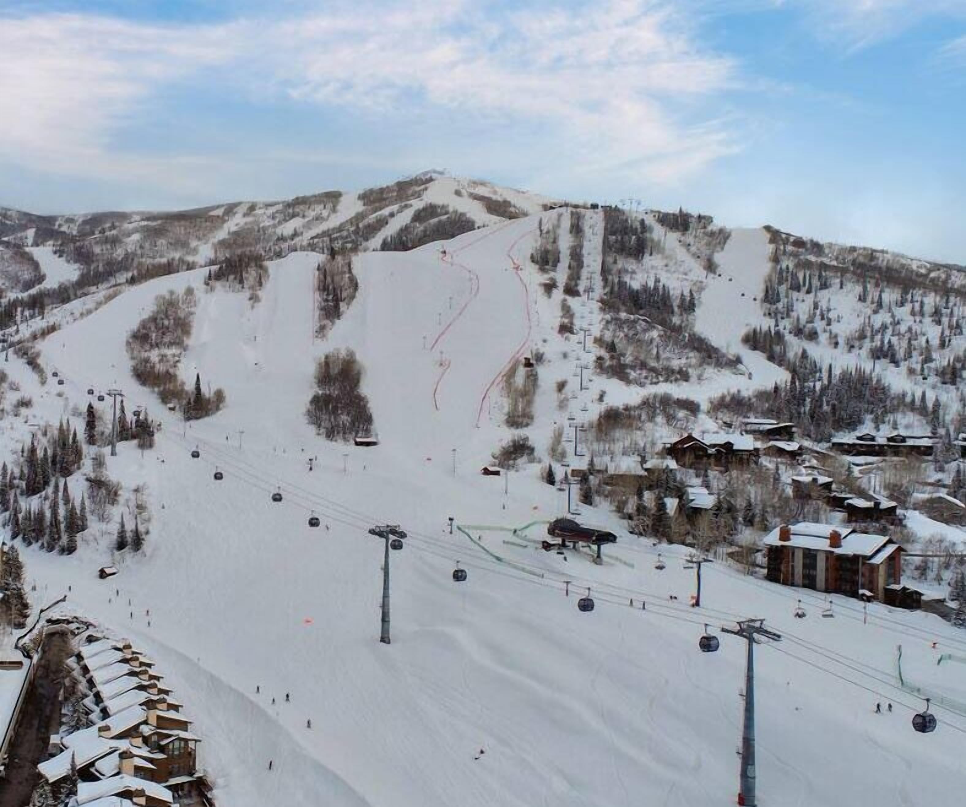 A ski resort with a chairlift, snow-covered slopes, and buildings in the background.