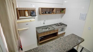 Una cocina compacta con un lavamanos integrado, estantes de madera y una encimera.