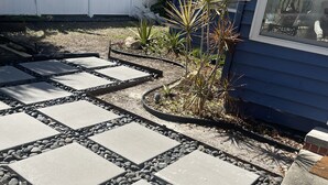 Un chemin de jardin pavé de dalles de pierre, bordé de gravier.
