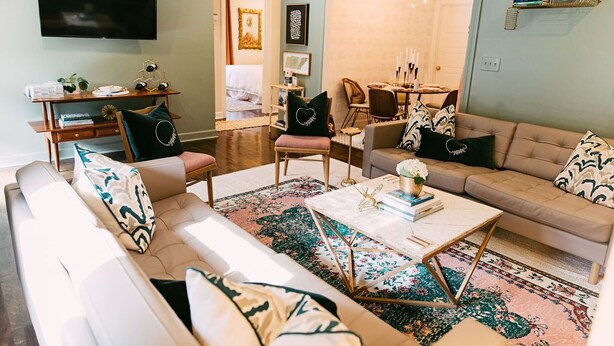 A living room with a sofa, armchairs, a coffee table, and a TV.