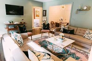 Ein Wohnzimmer mit einer Couch, Sesseln, einem Couchtisch und einem Fernseher.