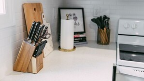A kitchen with a wooden knife block, a framed picture, and a spice rack.