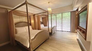 A four-poster bed with a canopy, a chandelier, and a large window with curtains.