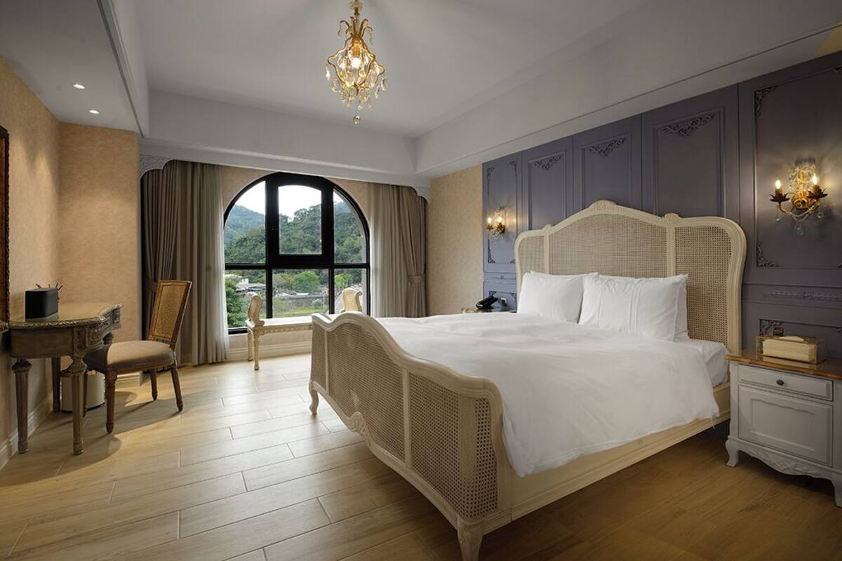 Ampia camera da letto con un letto grande, una scrivania e una sedia, con vista attraverso una grande finestra.