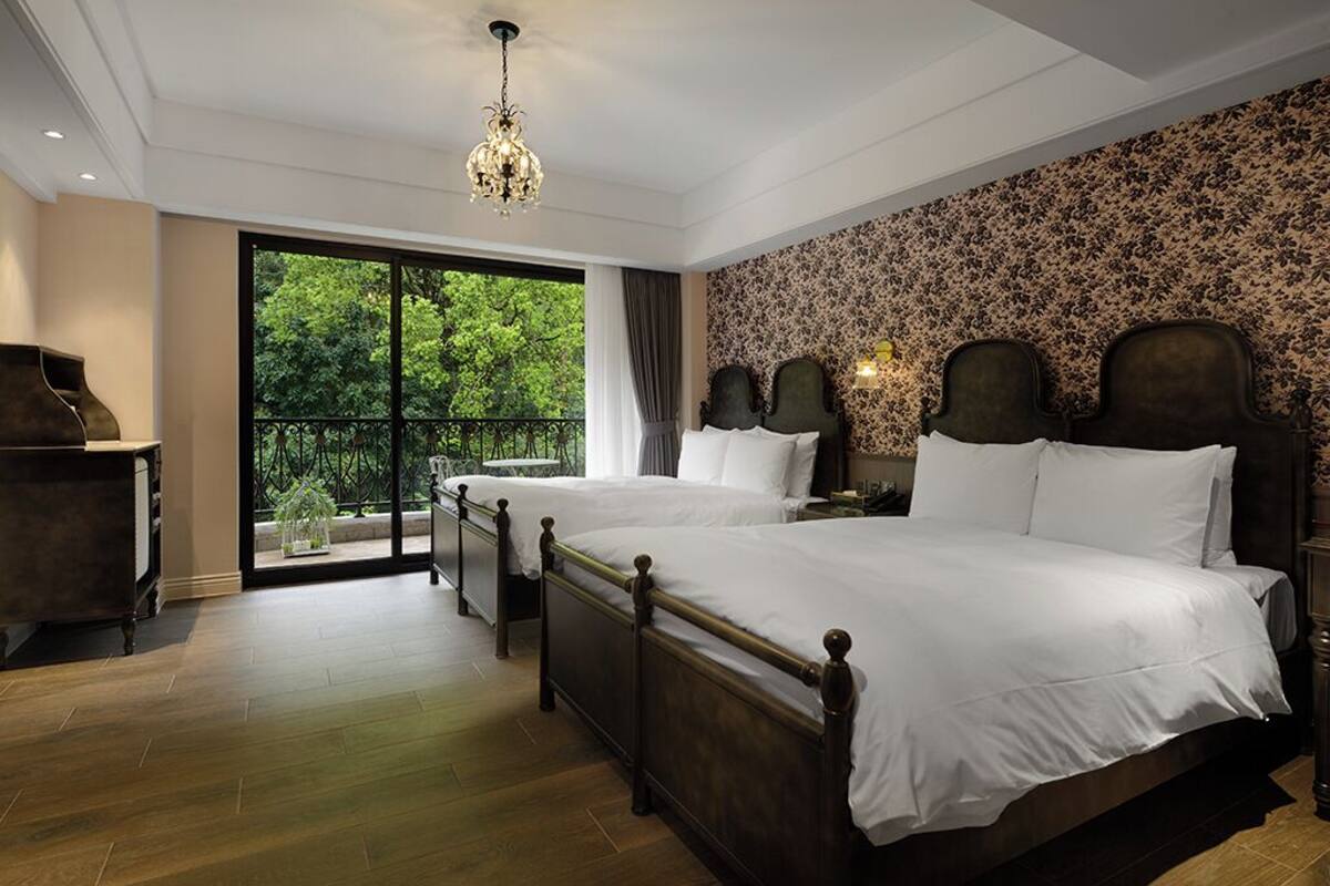 Camera da letto con due letti, un lampadario, vista attraverso una grande finestra e un balcone.