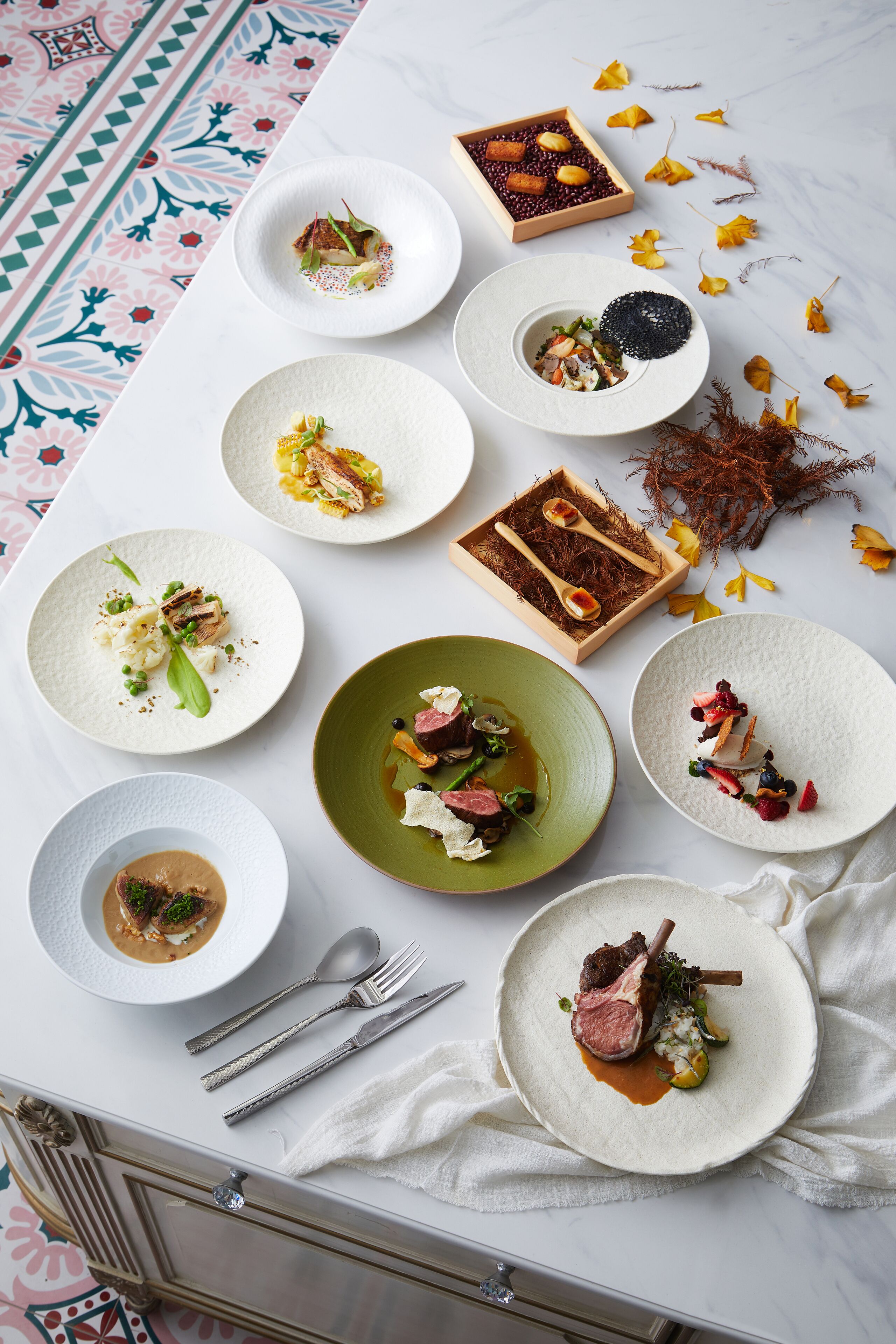 A dining table with various plates of food, utensils, and decorative elements.