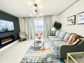 Un salon moderne avec une cheminée, un canapé, une table basse et un téléviseur.
