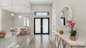 A modern kitchen with white bar stools, a dining table, and a large window. - Luxury Lakefront Oasis w/ Heated Pool & Spa (Cape Coral)