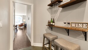 A bar area with stools, shelves holding bottles and glasses, and a 'WINE' sign. - 4BD Condo w/Parking & Game Room (Chicago)