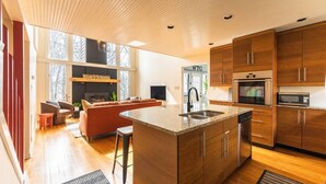 Uma cozinha moderna com armários de madeira, bancada de granito e eletrodomésticos de aço inoxidável.