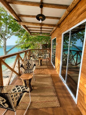 A wooden deck with outdoor seating, large windows, and a view of the sea. - Freedom Beach Hotel (Cartagena)