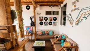 A cozy living room with wooden furniture, a coffee table, and a wall decorated with vinyl records and a winged heart sign. - Freedom Beach Hotel (Cartagena)