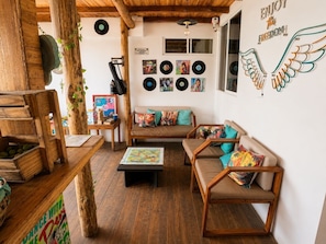A cozy living room with wooden furniture, a coffee table, and a wall decorated with vinyl records and a winged heart sign.