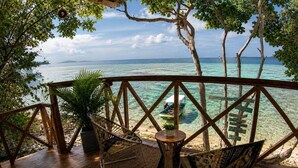 A wooden deck with wicker chairs and a small table, overlooking a clear turquoise sea and a distant island. - Freedom Beach Hotel (Cartagena)