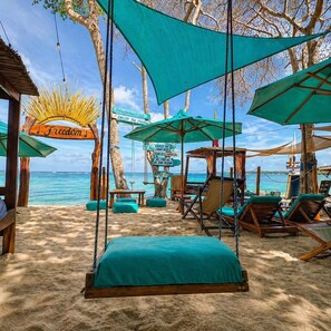 A beach setting with a swing chair, lounge chairs, and a sign reading 'Freedom.' - Freedom Beach Hotel (Cartagena)