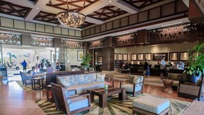 A spacious lobby with a reception desk, seating areas, and a large chandelier.