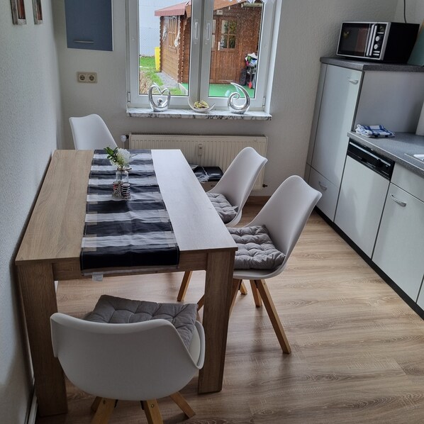 Eine moderne Küche mit weißen Schränken, einer Mikrowelle und einem Essbereich mit Tisch und Stühlen.