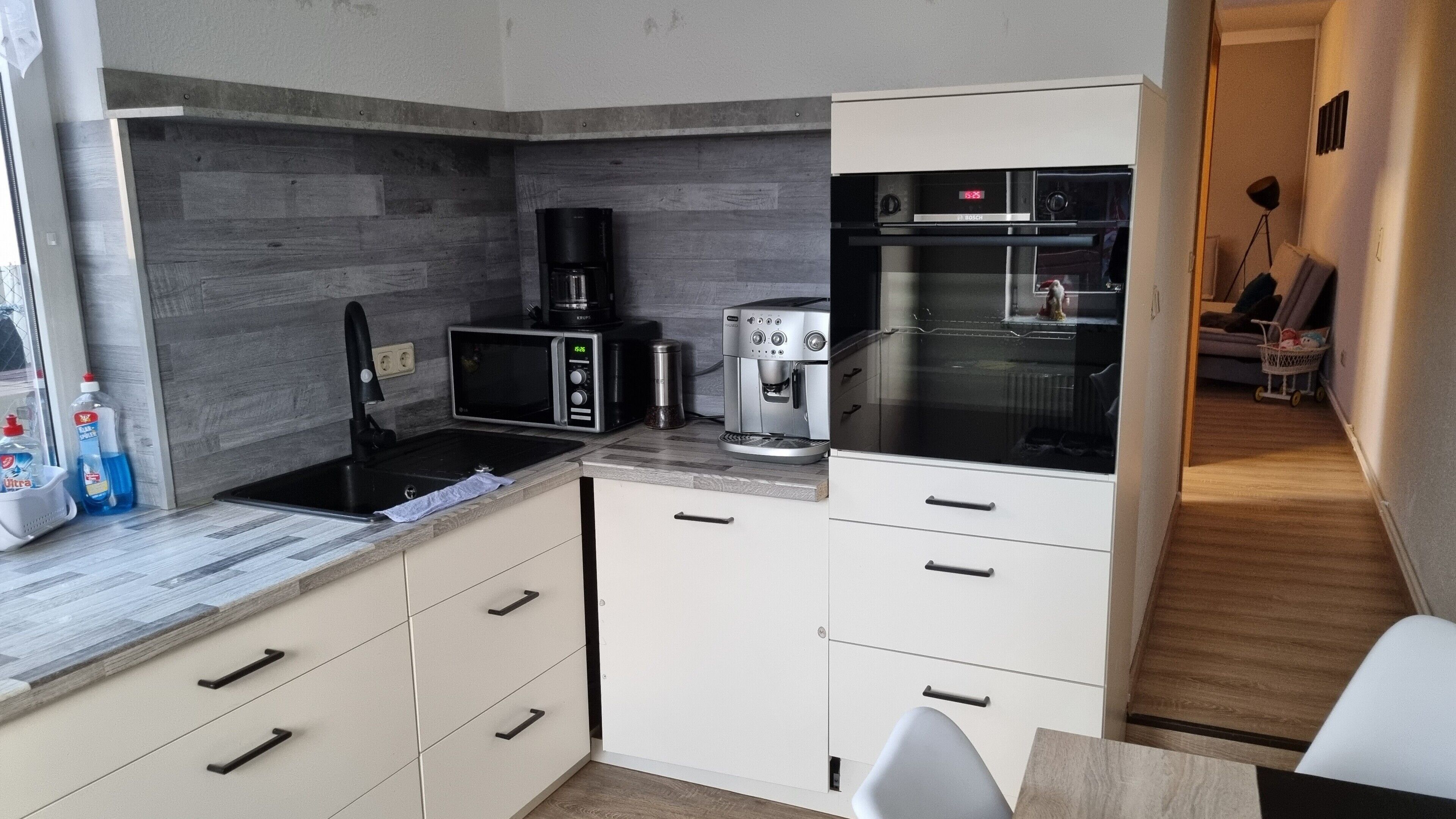 A compact kitchen with a microwave, coffee maker, and Bosch oven.