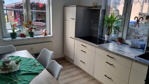 A kitchen with a dining table, white cabinets, a black stove, and a window with decorations.