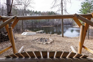 A wooden deck with a view of a lake and a fire pit area.