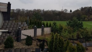 A patio area with a table and chairs, a stone wall, and a view of a green field. - Holiday Apartment "Lila Pause" with Private Terrace & Wi-Fi (Ellweiler)
