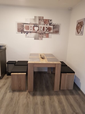A room with a wooden table and benches, a 'HOME' sign on the wall, and a trash bin. - Holiday Apartment "Lila Pause" with Private Terrace & Wi-Fi (Ellweiler)