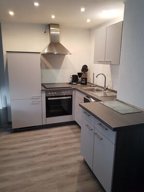 A modern kitchen with a built-in oven, a stovetop, a sink, and a coffee maker. - Holiday Apartment "Lila Pause" with Private Terrace & Wi-Fi (Ellweiler)